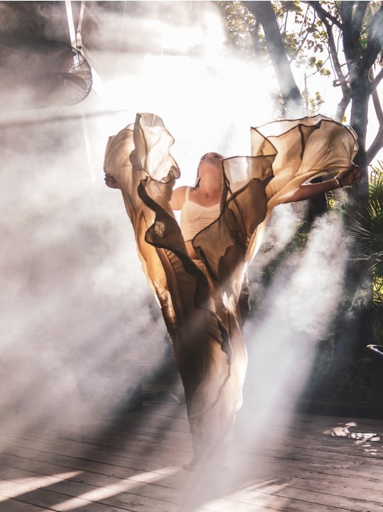 María bailando con una tela entre rayos de luz